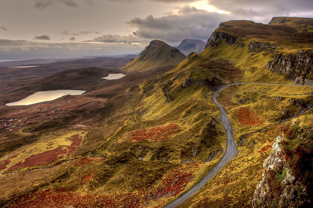 Winding mountain road through the Quiraing hills on the Isle of Skye with lochs and rocky cliffs